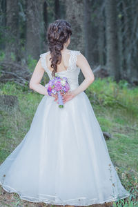 Young woman with arms outstretched standing against trees