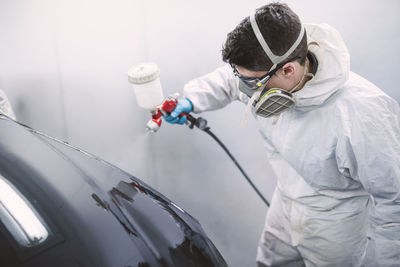 Auto painter painting a car inside a paint booth