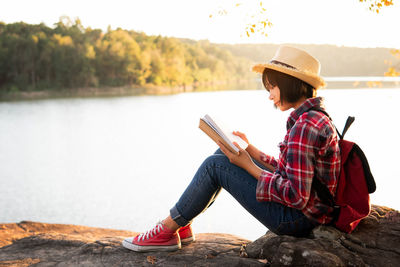 Side view of woman sitting by lake