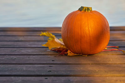 Pumpkin and autumn leaves on wooden boards.