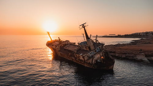 Fishing boat in sea against sky during sunset