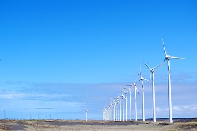 Wind turbines on field against sky