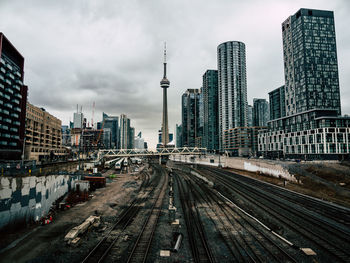 Railroad tracks amidst buildings in city against sky