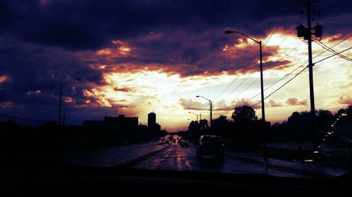 Silhouette city against dramatic sky during sunset