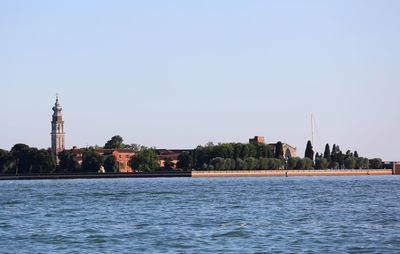 Sea by buildings against clear sky