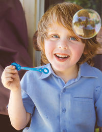 Portrait of smiling boy holding wand while looking at bubble