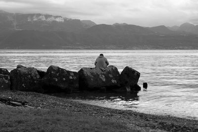 Rocks sitting on rock by sea against sky