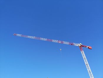 Low angle view of crane against clear blue sky