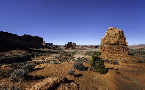 Rock formations on landscape against clear blue sky