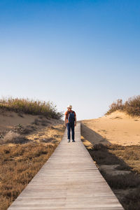 Rear view of man walking on footpath against sky