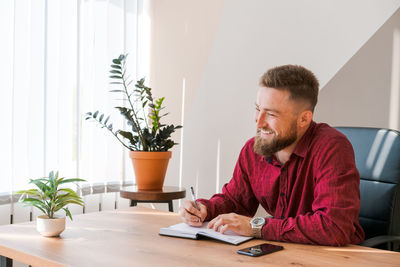 Portrait handsome smiling man with beard, working in office on some project, he