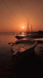 Sailboats moored on sea against sky during sunset