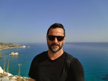 Portrait of young man looking away against sea