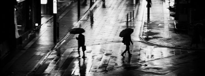 Rear view of people walking on street amidst buildings in city