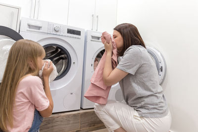 Mother and daughter smelling washed clothes at home