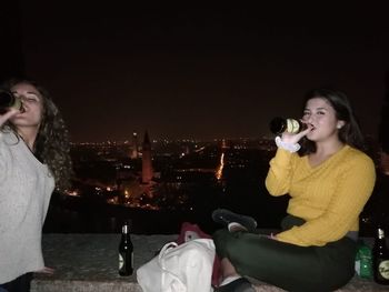 Beautiful young woman sitting at illuminated night