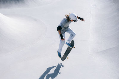 Skateboarder doing stunt with skateboard on sunny day