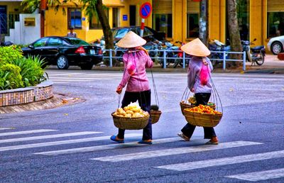 Rear view of women walking on road in city