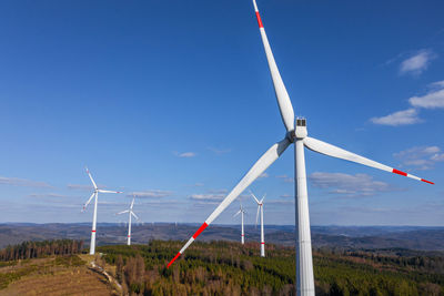 Wind turbines on field against sky