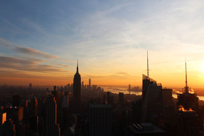 Modern buildings in city against sky during sunset