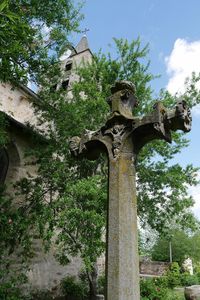 Low angle view of cross statue against trees