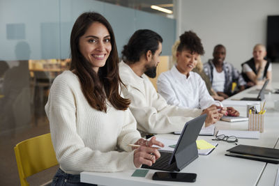 Smiling woman sitting during business meeting and looking at camera