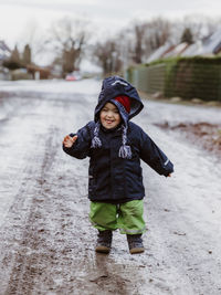 Toddler girl walking on dirt road during winter