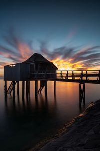 Silhouette pier over sea against sky during sunset