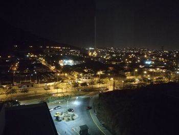 High angle view of illuminated road amidst buildings in city at night