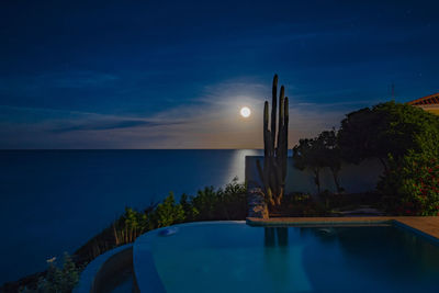 Swimming pool by sea against sky at night