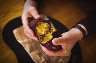 Close-up of hand breaking sweet potato at table