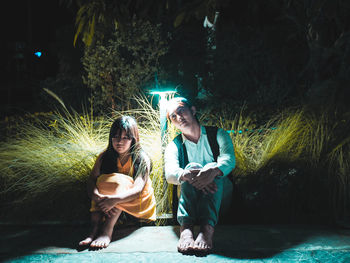 Man and girl sitting by illuminated lighting equipment 