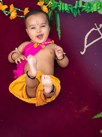 Cute indian boy dresses as lord rama with bow and flowers from top angle