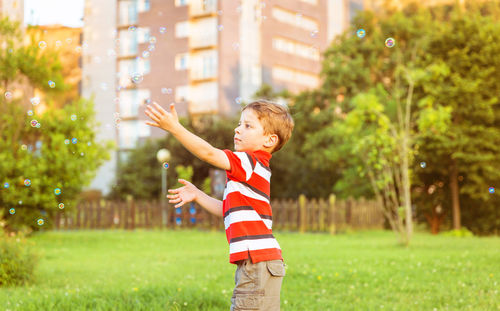 Side view of boy standing against plants