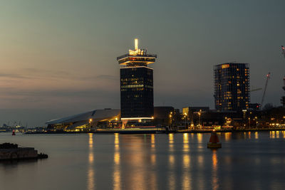 Illuminated buildings by sea against sky at night amsterdam