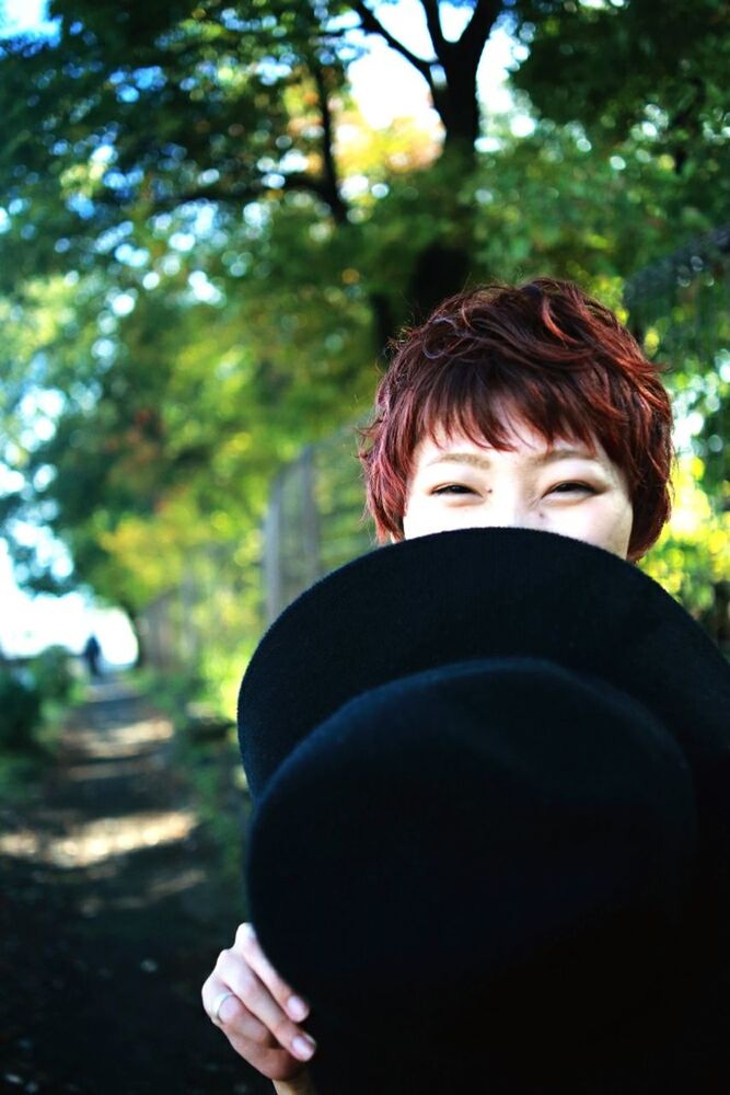 lifestyles, leisure activity, tree, focus on foreground, headshot, casual clothing, childhood, waist up, park - man made space, person, rear view, day, head and shoulders, outdoors, holding, young adult, elementary age, brown hair