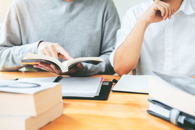Midsection of man reading book on table