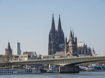 Bridge over river in city against clear sky