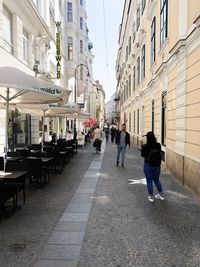 Rear view of people walking on street amidst buildings in city