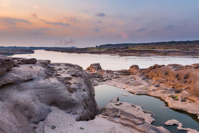 Rocks on shore against sky during sunset