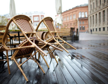 Chairs on wet wooden floor in city