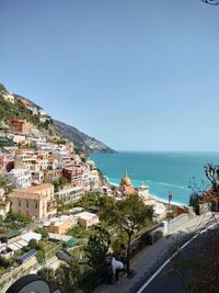 High angle view of townscape by sea against clear blue sky