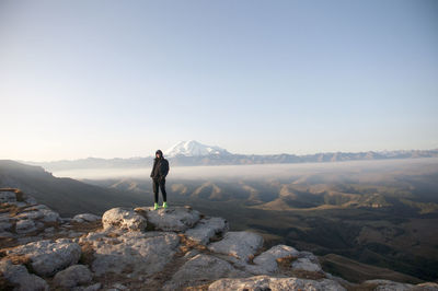 Man standing on rock against sky