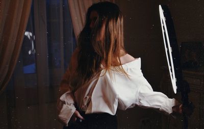 Rear view of woman standing by window