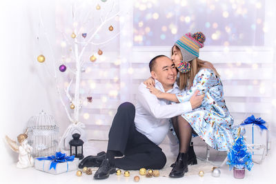 Happy father with daughter by artificial christmas tree on floor