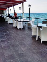 Chairs and tables in restaurant at beach against sky