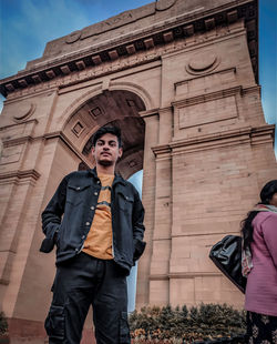 Low angle portrait of teenager standing against india gate