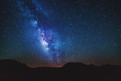 Silhouette landscape below starry sky