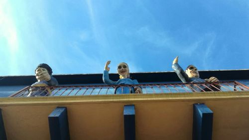 Low angle view of people sitting against sky