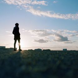 Silhouette man walking on field against sky